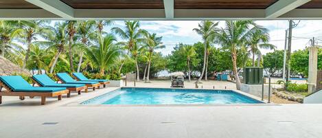 Un espace piscine avec des chaises longues et des palmiers.
