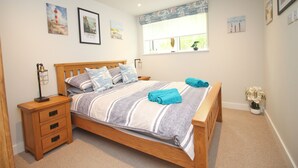 Quarto com cama de madeira, mesa de cabeceira e janela com cortinas.