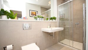 Uma casa de banho moderna com sanita, lavatório e cabine de duche em vidro.