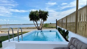 A swimming pool with steps leading into it, surrounded by a wooden fence and a couch.