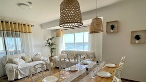 A dining area with a wooden table set for four, surrounded by white chairs.