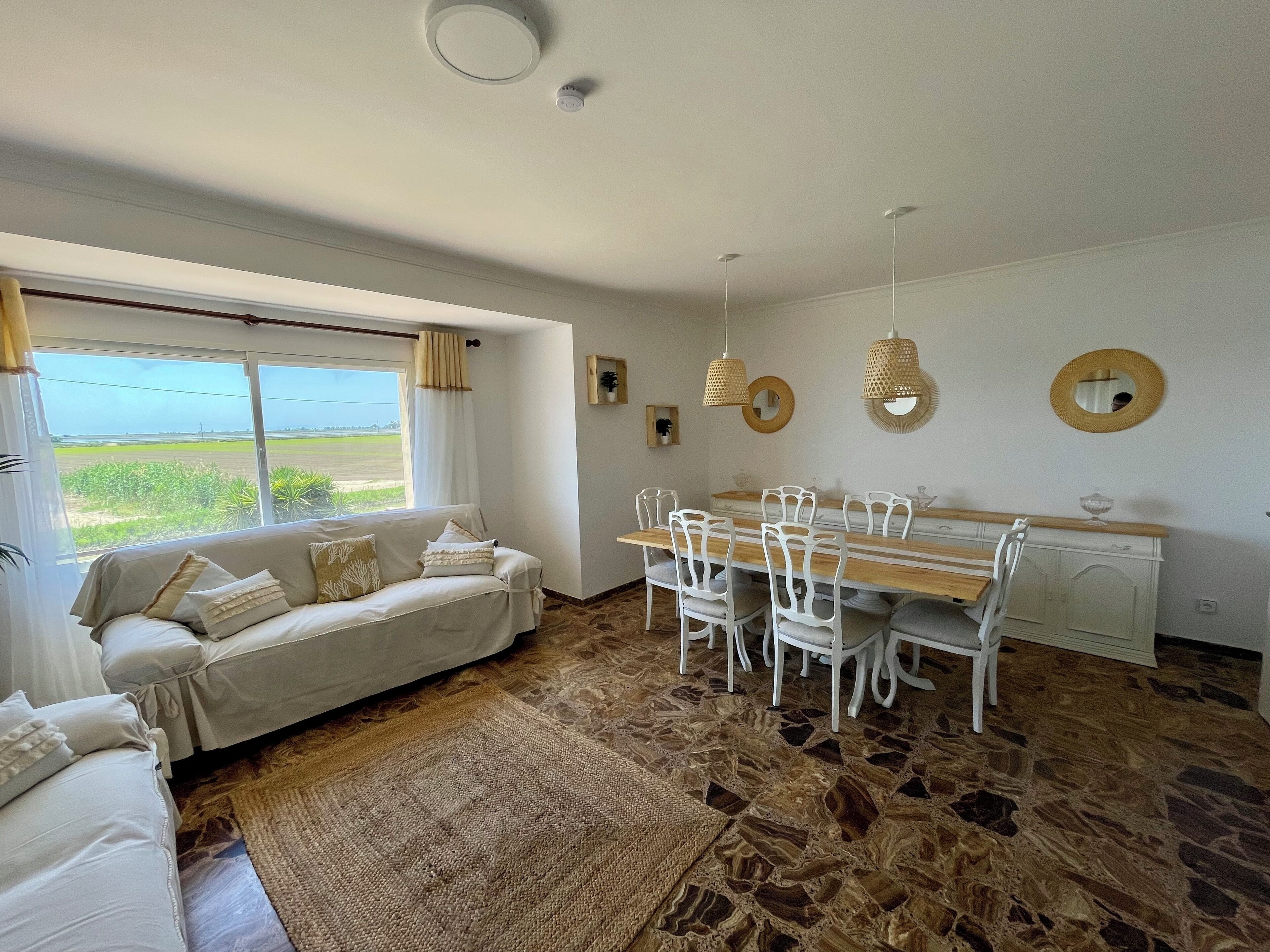 A room with a sofa, dining table, chairs, and a view of the outdoors.
