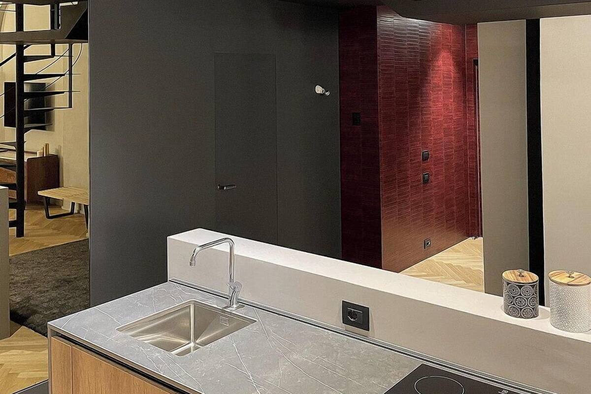 Uma cozinha moderna com bancada de mármore, pia de aço inoxidável e forno embutido.