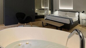 Moderni hotellihuone, jossa on suuri kylpyamme, sänky, työpöytä ja tuoli.