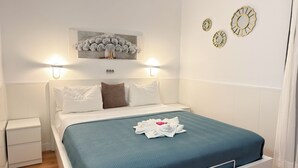 A neatly arranged hotel room with a bed, a nightstand, a wall-mounted light, and a decorative mirror.