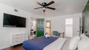 A bedroom with a bed, a desk, a chair, a television, and a door. - Pool Table  Luxury 1Bed Apt in Downtown & Heights (Houston)