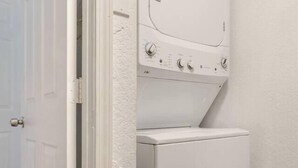 A laundry room with a washer and dryer, a door, and a textured wall. - Pool Table  Luxury 1Bed Apt in Downtown & Heights (Houston)