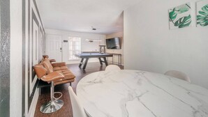A room with a pool table, a sofa, a dining table, and a TV. - Pool Table  Luxury 1Bed Apt in Downtown & Heights (Houston)