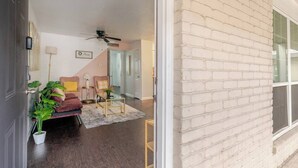 A living room with a sofa, armchairs, a coffee table, and a ceiling fan. - Pink 1BHK, 5 miles from Downtown + Free Parking (Houston)