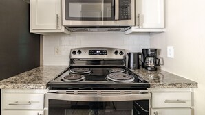 Eine Küche mit Edelstahlherd, Backofen, Mikrowelle und Kaffeemaschine.