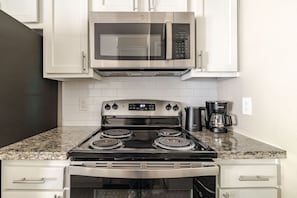 A kitchen with a stainless steel stove, oven, microwave, and a coffee maker. - Gothic Blush King 2Bed near Texas Medical Center & in front of NRG Stadium (Houston)