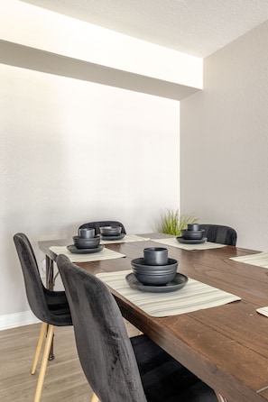 A dining table with black chairs and a plant in the corner. - Gothic Blush King 2Bed near Texas Medical Center & in front of NRG Stadium (Houston)