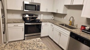 A kitchen with white cabinets, a stainless steel oven, a microwave, a dishwasher, and granite countertops. - Charming 3Bed 2Bath apt in front of NRG & near TMC (Houston)