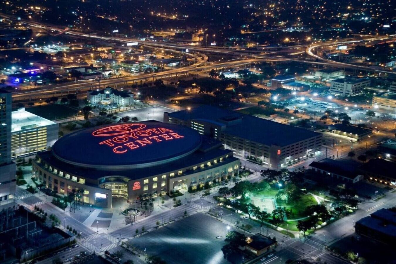 En stor, rund bygning med et tydeligt Toyota Center skilt øverst, omgivet af parkeringsområder og tilslutningsveje.