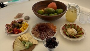A table with various food items and a bottle of juice on a boat with a view of the ocean. - Luxury 47’ Leopard Power Catamaran - Bahamas (Nassau)