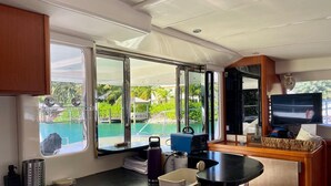 A compact kitchen with a sink, a small refrigerator, and a window offering a view of a pool and greenery. - Luxury 47’ Leopard Power Catamaran - Bahamas (Nassau)