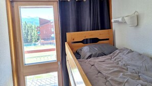 Ein Einzelbett mit Holz-Kopfteil in einem Zimmer mit Fenster.