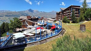 Ein Bergurlaubsort mit einer Seilbahn, traditionellen Holzhäusern und einem modernen Hotel.