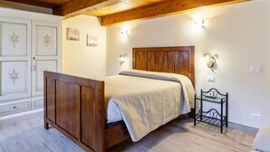 A bedroom with a wooden bed, white walls, and a wooden ceiling. There are two wall-mounted light fixtures and a small bedside table. - Cozy Rustico for 6/7 people with umbrella in Lido di Camaiore (Camaiore)