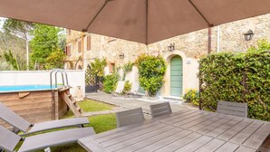 An outdoor patio with a table and chairs, a pool, and a stone building in the background. - Cozy Rustico for 6/7 people with umbrella in Lido di Camaiore (Camaiore)