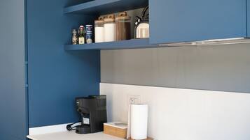 Una cucina moderna con mobili blu, una macchina da caffè e barattoli portaoggetti sugli scaffali.