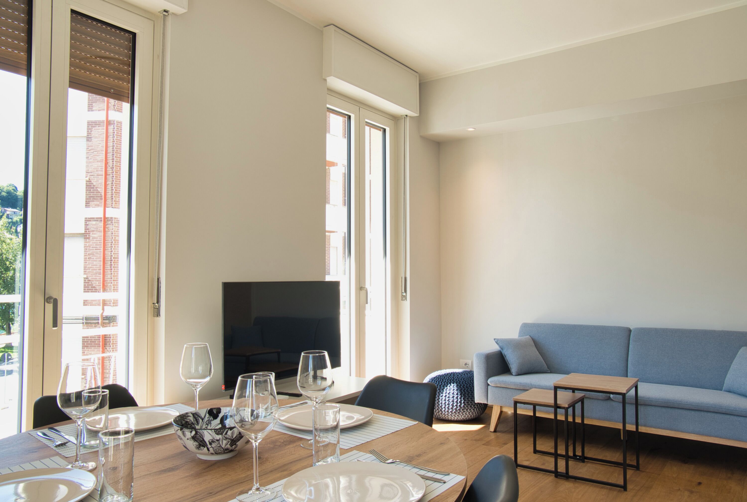 Un soggiorno moderno con zona pranzo, divano e televisione.