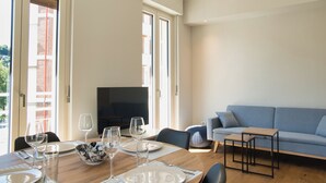 A modern living room with a dining area, a sofa, and a television.
