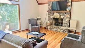 Ein gemütliches Wohnzimmer mit Kamin aus Stein, einer bequemen Couch und einem Fernseher über dem Kamin.