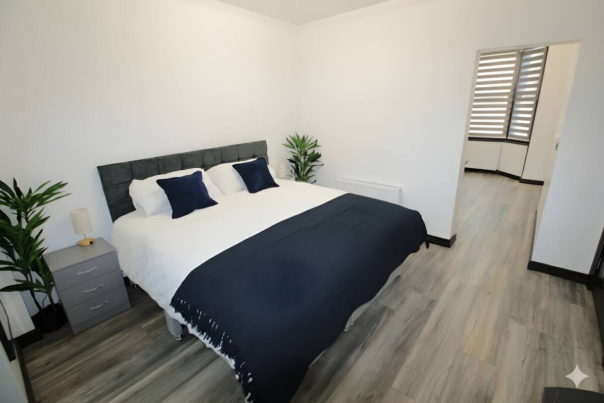 A bedroom with a bed, bedside tables, and a potted plant.