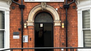 A red brick building with a large sign for 'Simply Stay' above the entrance.