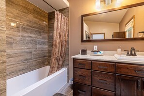 A modern bathroom with a bathtub, wooden vanity, and a large mirror. - Ouray Getaway: Walk to Hot Springs, Trails & Shops (Ouray)
