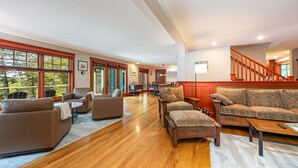 A spacious living room with hardwood flooring, a large sofa set, and a staircase leading to an upper level. - Windward Lodge- stunning, dog-friendly private waterfront retreat. Seasonal dock (Woolwich)