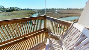 A wooden deck with a bench and a view of a river and marshland. - One Marsh Creek by Tybee Vacation Rentals (Tybee Island)