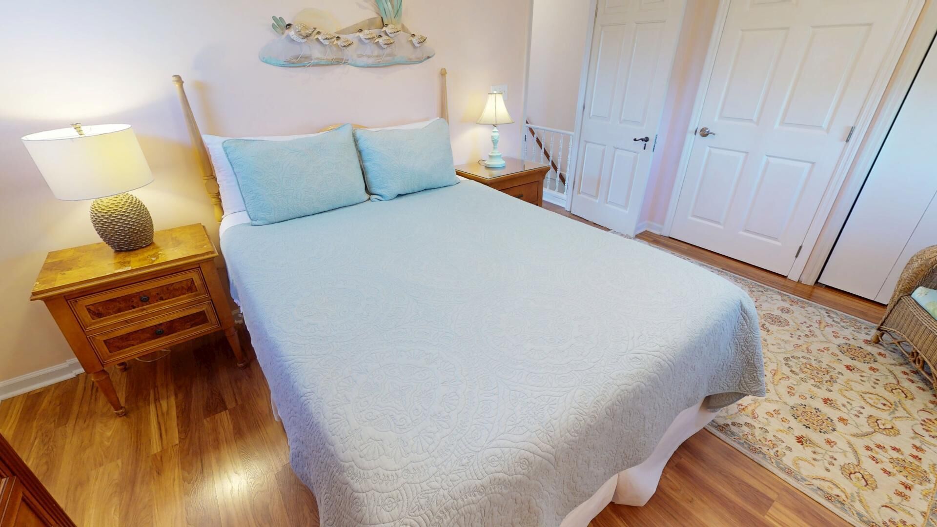 Un dormitorio ordenado con cama, mesitas de noche y una puerta.