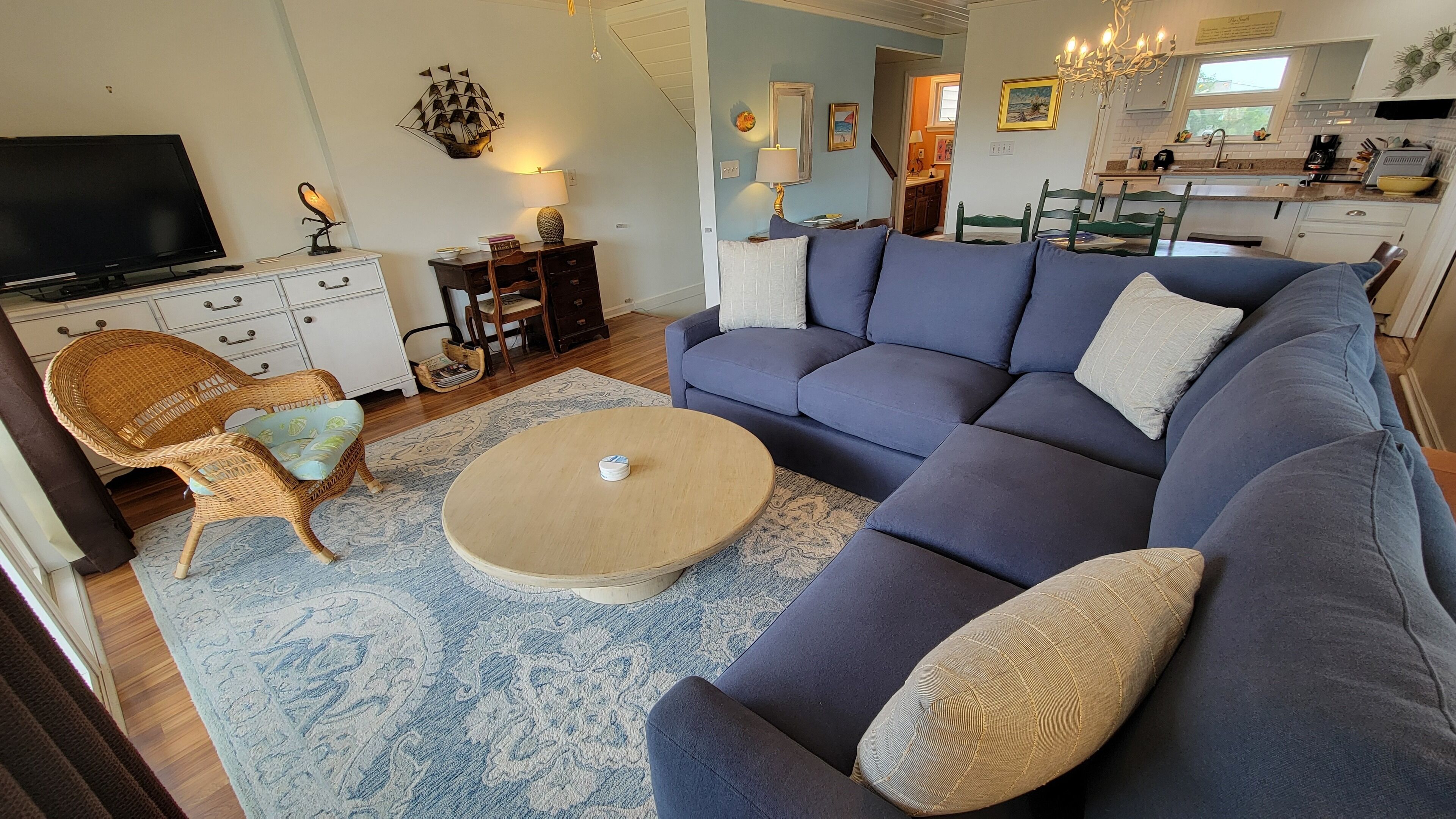 Una sala de estar con un sofá, una mesa de centro, un televisor y un comedor con sillas y una mesa.