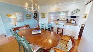 A dining room with a wooden table, chairs, and a chandelier.