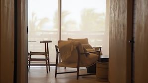 A room with a wooden chair, a small table, and a sofa with a blanket. - Minimalist elegance by the beach (Zihuatanejo)