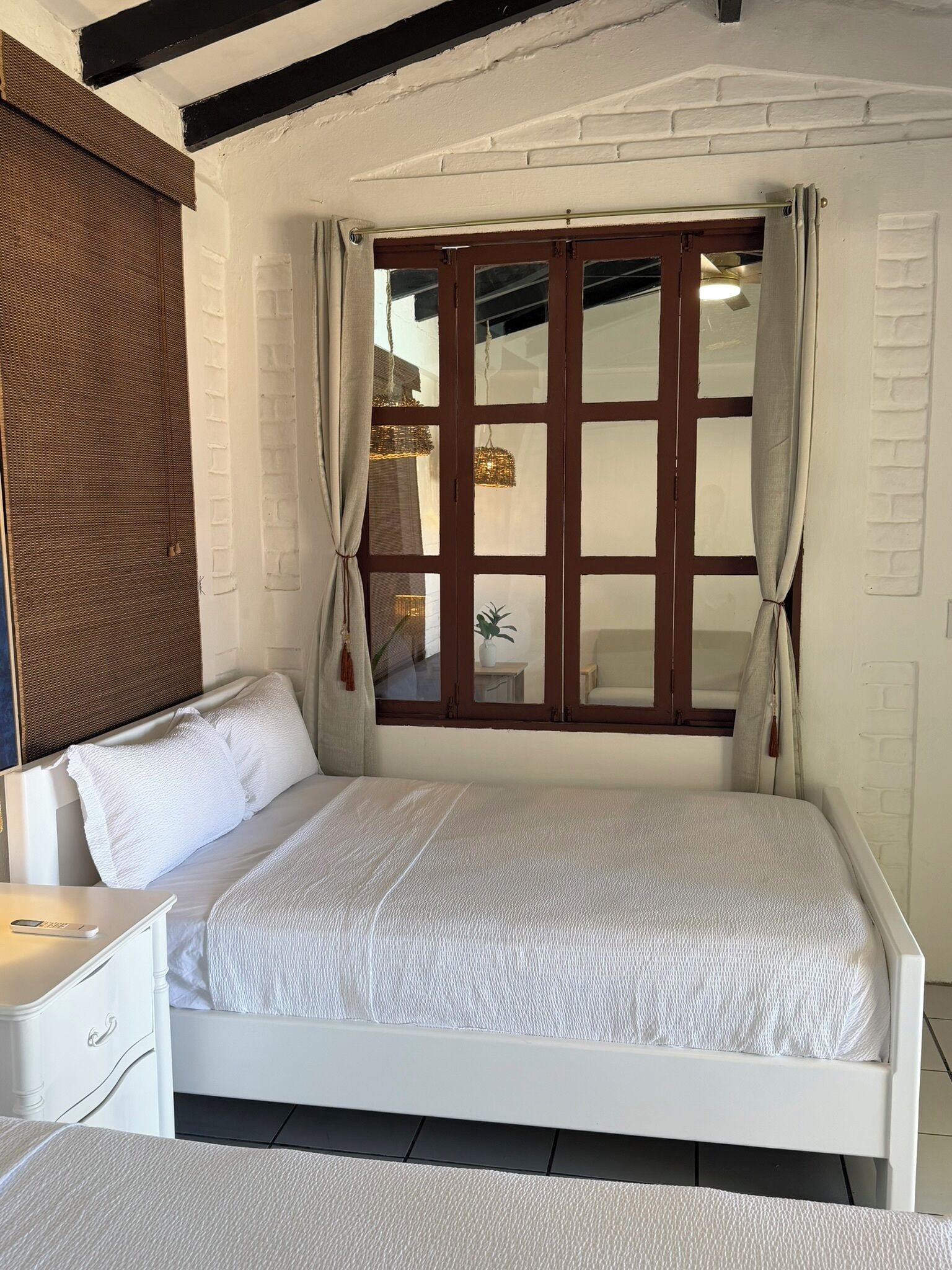 Un dormitorio con cama, mesita de noche, ventana con cortinas y pared con textura.