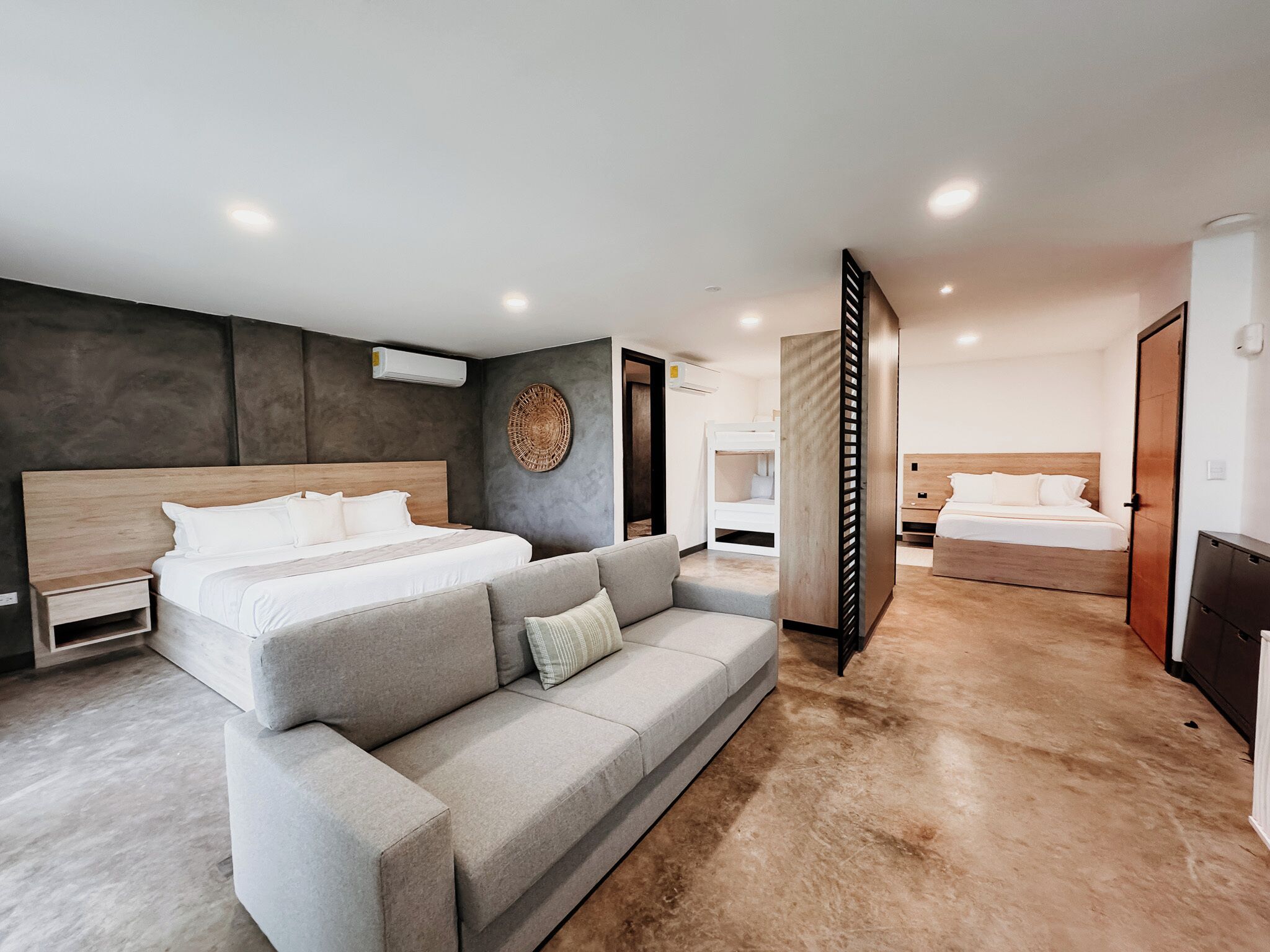 Een moderne hotelkamer met een groot bed, een grijze bank en een houten hoofdeinde.