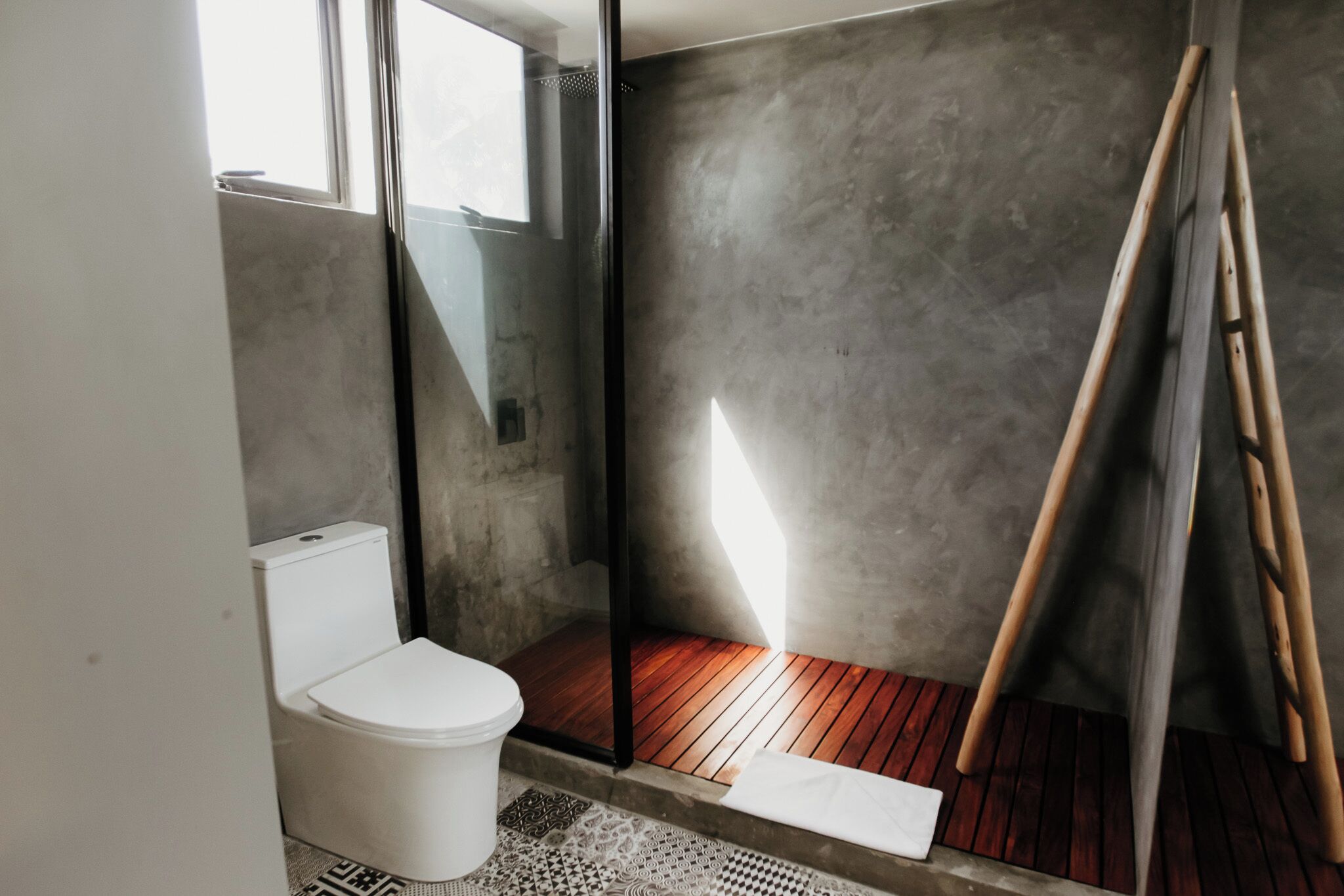 Un baño moderno con inodoro blanco, ducha con puerta de cristal y suelo de madera.