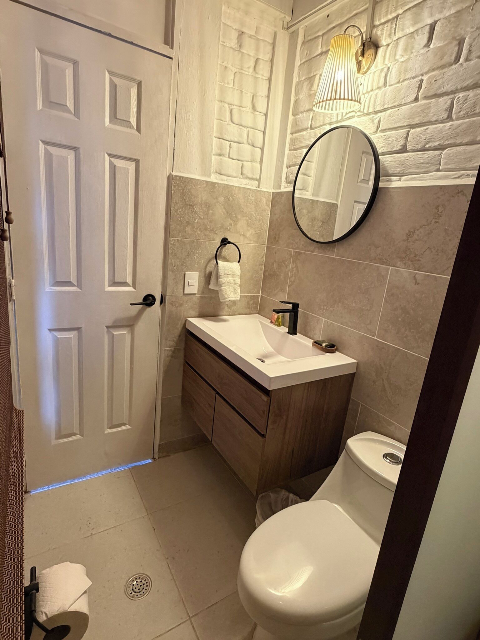 Ein Badezimmer mit weißer Tür, Waschbecken, Spiegel und Toilette.
