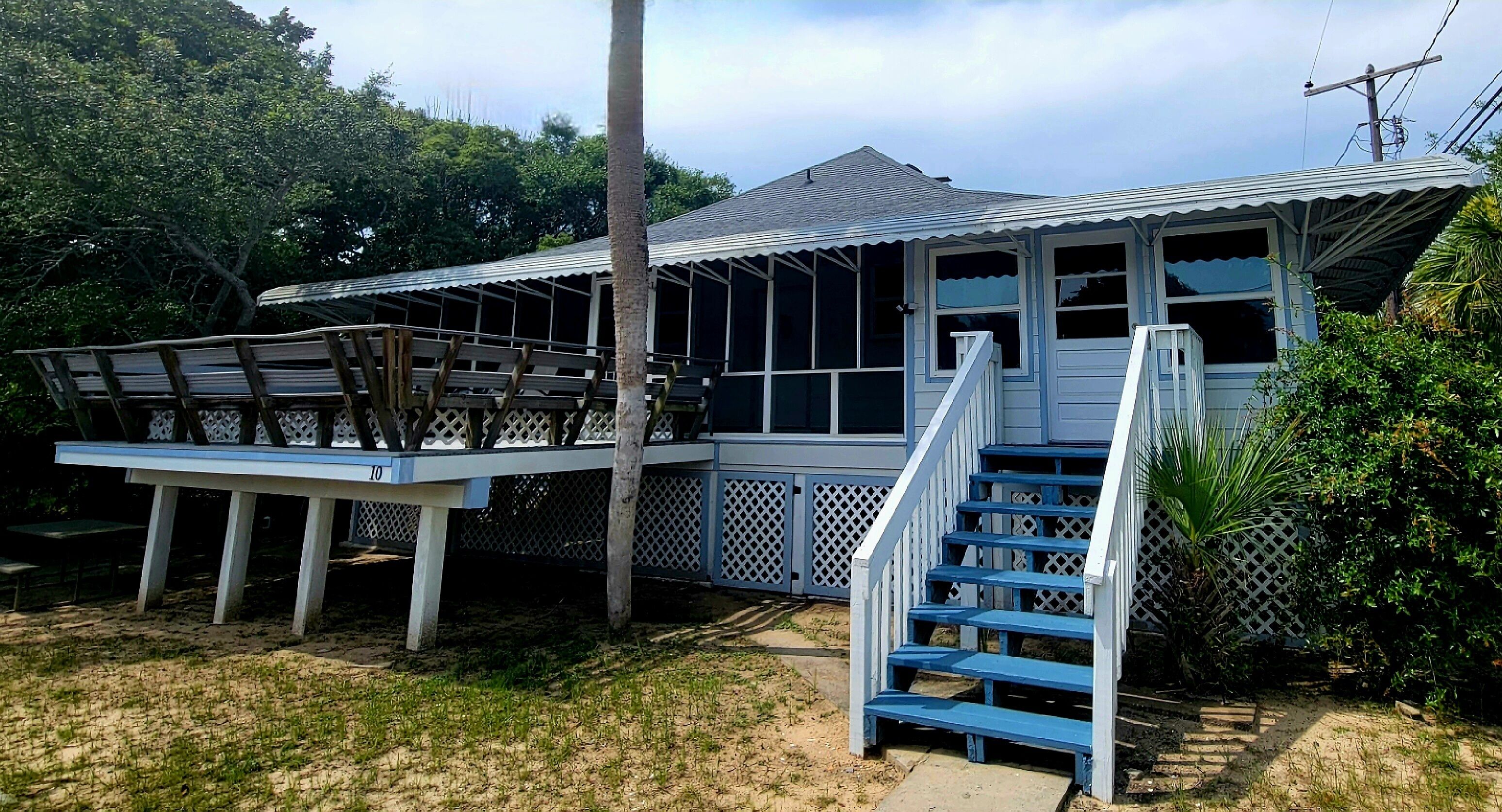 A house with a covered porch, a staircase, and a fenced deck area.