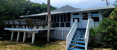 A house with a covered porch, a staircase, and a fenced deck area.