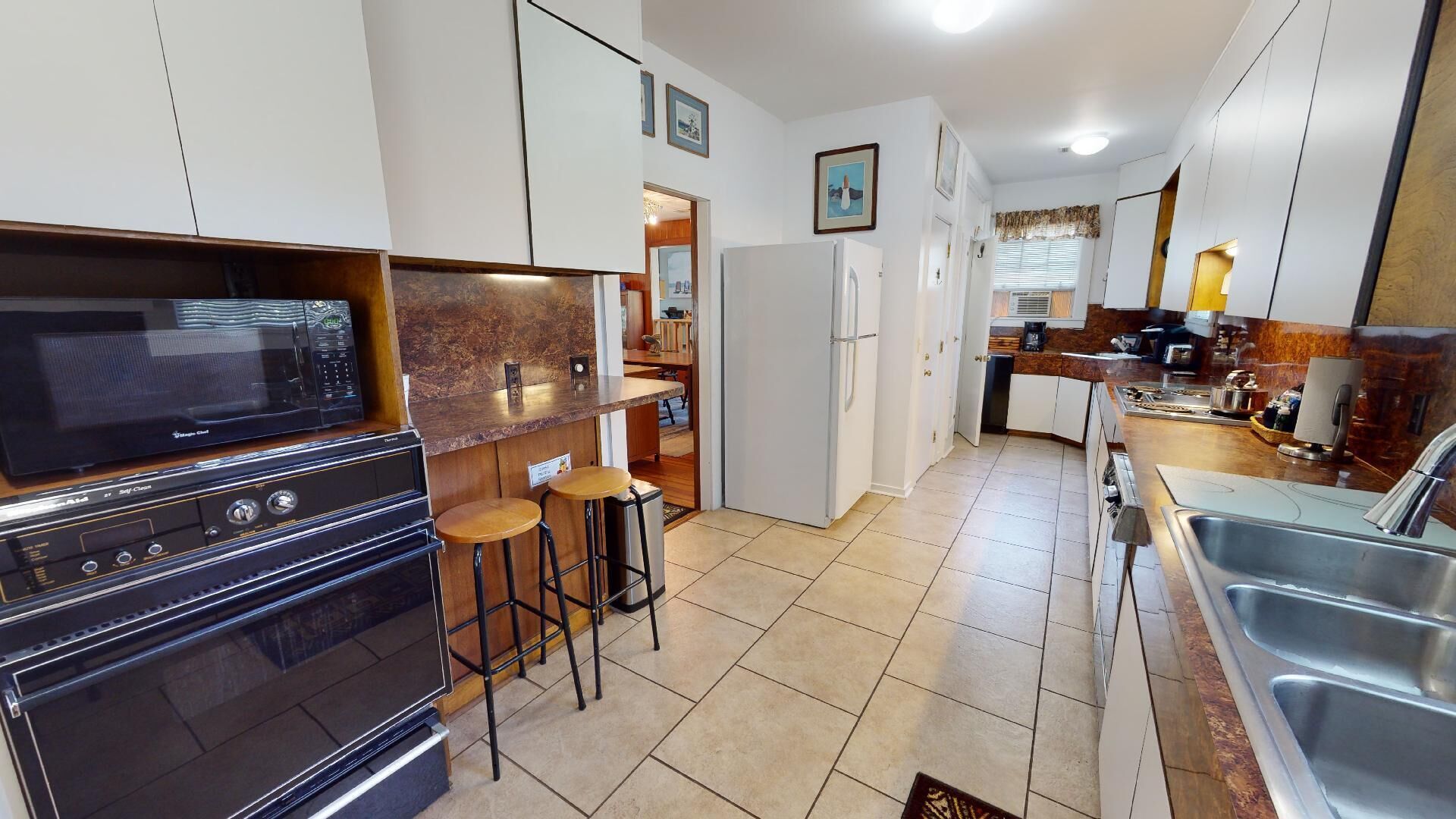 Una cocina compacta con microondas, estufa y taburetes de bar.