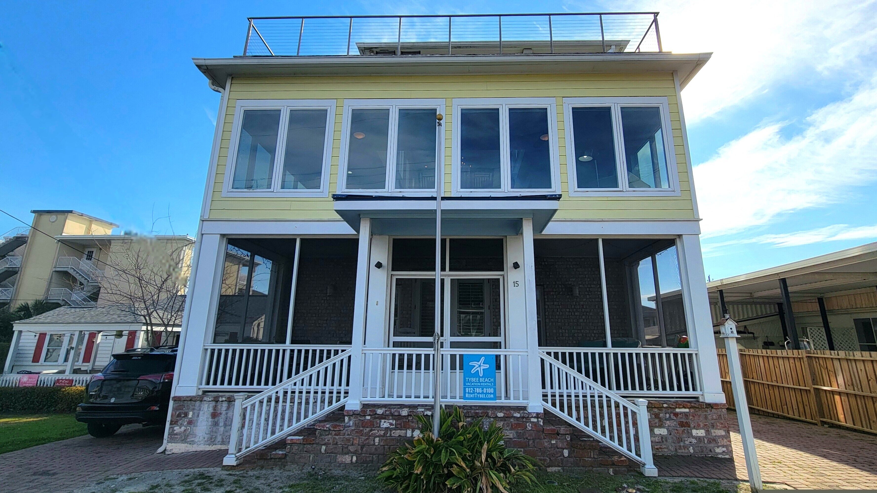 Een gebouw met twee verdiepingen, een balkon, een trap en een bord met daarop Tybee Beach Vacation Rentals.
