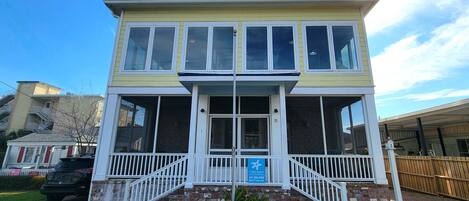 Een gebouw met twee verdiepingen, een balkon, een trap en een bord met daarop Tybee Beach Vacation Rentals.