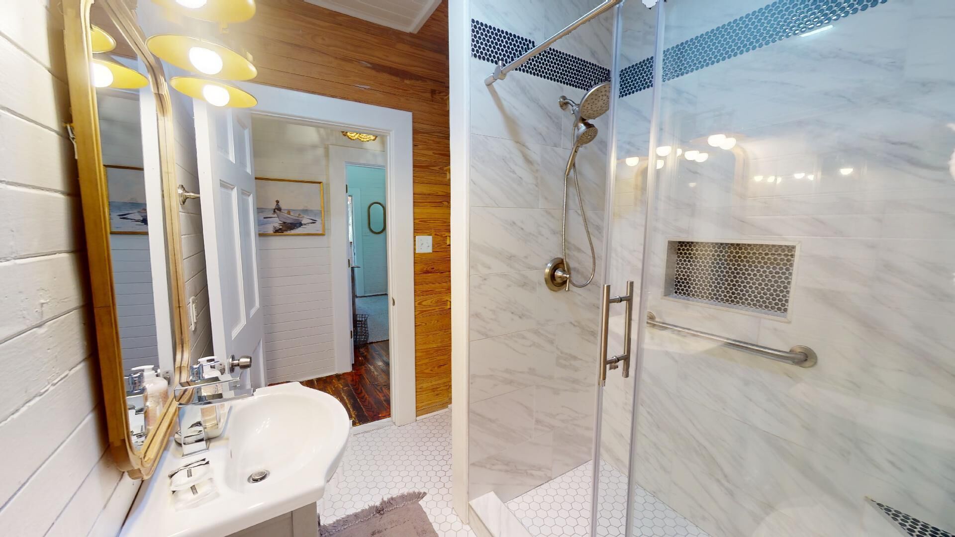 A bathroom with a white sink, a mirror, and a shower with a glass door.