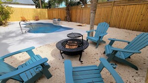 Un jardin avec une piscine, un foyer extérieur et des chaises Adirondack bleues.