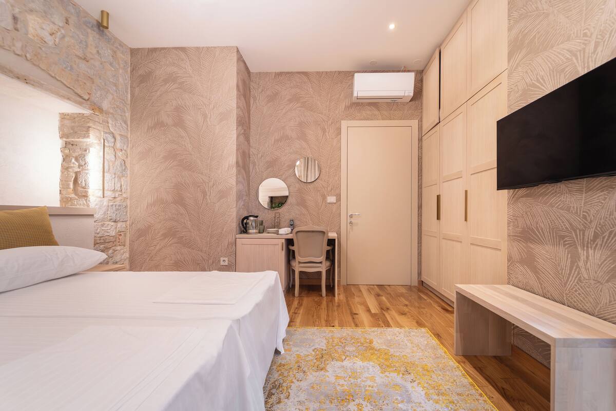 Un dormitorio con cama, escritorio, silla, televisión y armario.