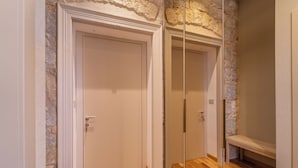 Un pasillo con pared de piedra, suelo de madera y puerta blanca.